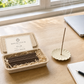 First Ink incense box with scent label open on a morning desk, stick burning in fluted ceramic holder